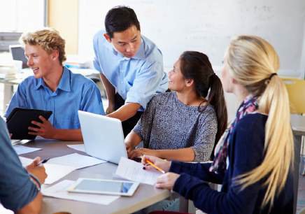 University students and an instructor collaborating around laptops and tablets