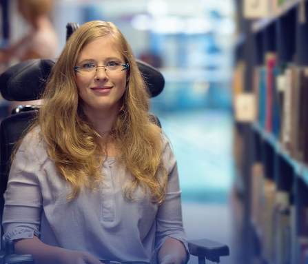 A student reading on a tablet between library shelves